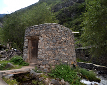 A square stone water mill near green hillside