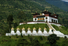 A temple at the base of a hillside, with eight stupas in front