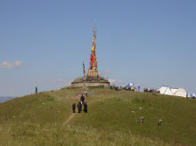 Locals walk toward a tall platform of colorful offerings being made to a local deity